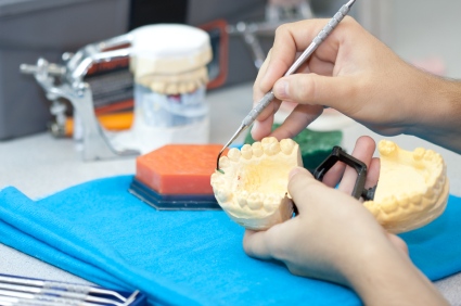 Dentist holding plastic model of mouth and using a dental explorer