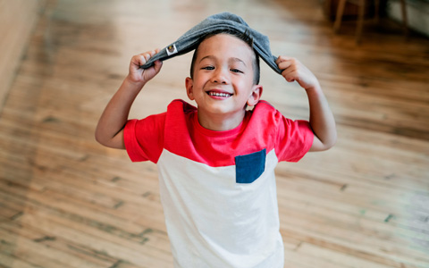 Happy kid in kitchen, smiling and holding dish towel 