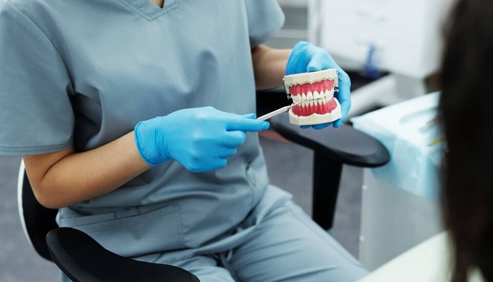 dentures being held by a dentist in blue scrubs