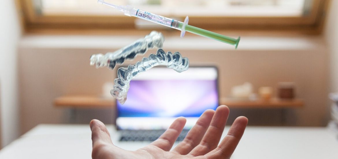 hand under a syringe pair of 3d printed teeth in front of a computer