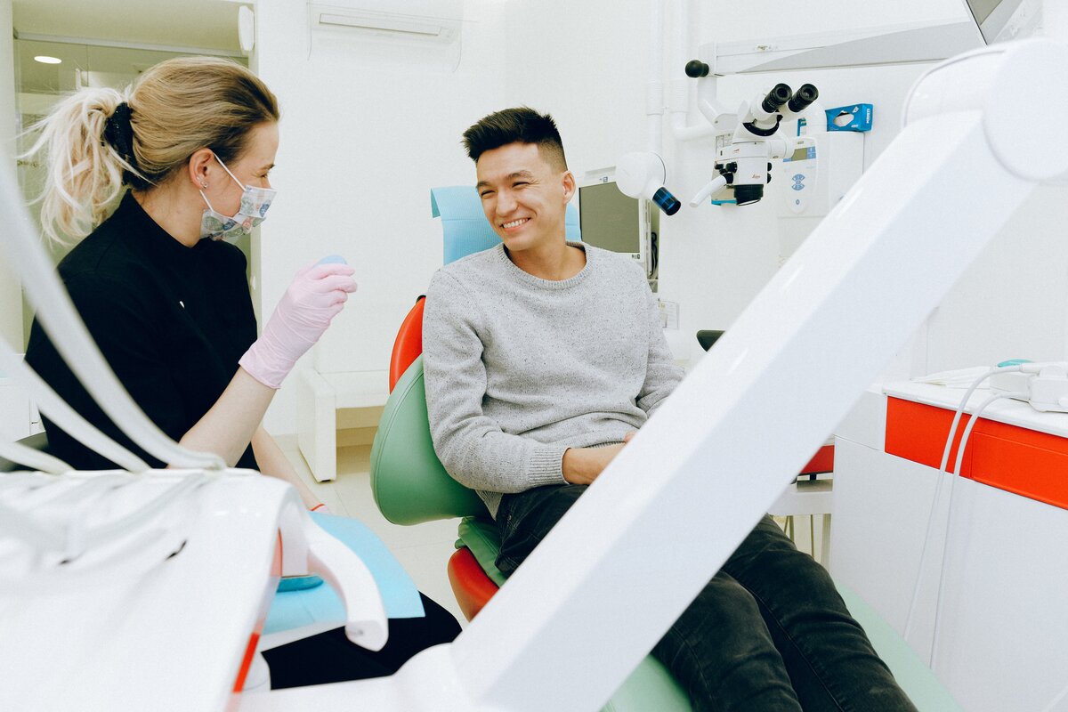 man in a dental chair smiling next to a female hygienist